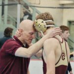 Coach and wrestler embrace after match.