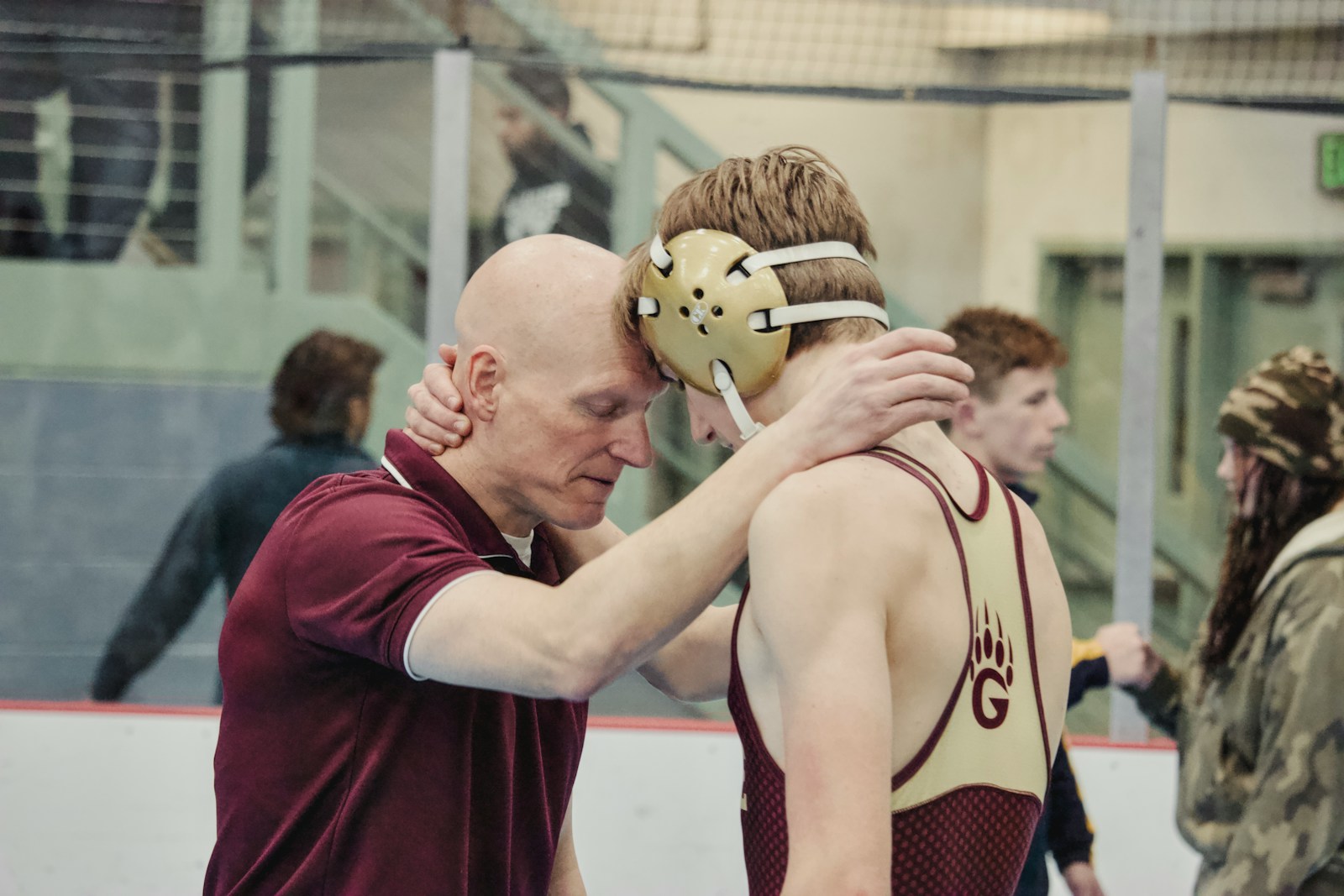 Coach and wrestler embrace after match.