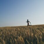 man in black jacket and black pants running on brown grass field during daytime