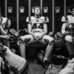 Football players sitting in a locker room.