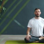 Man meditating in lotus pose on yoga mat