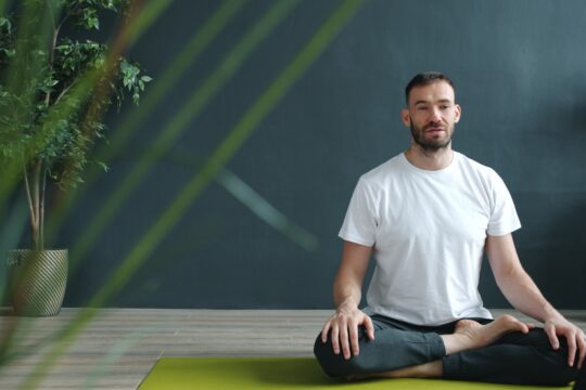 Man meditating in lotus pose on yoga mat