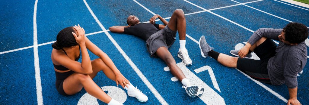 Athletes resting on a blue running track.